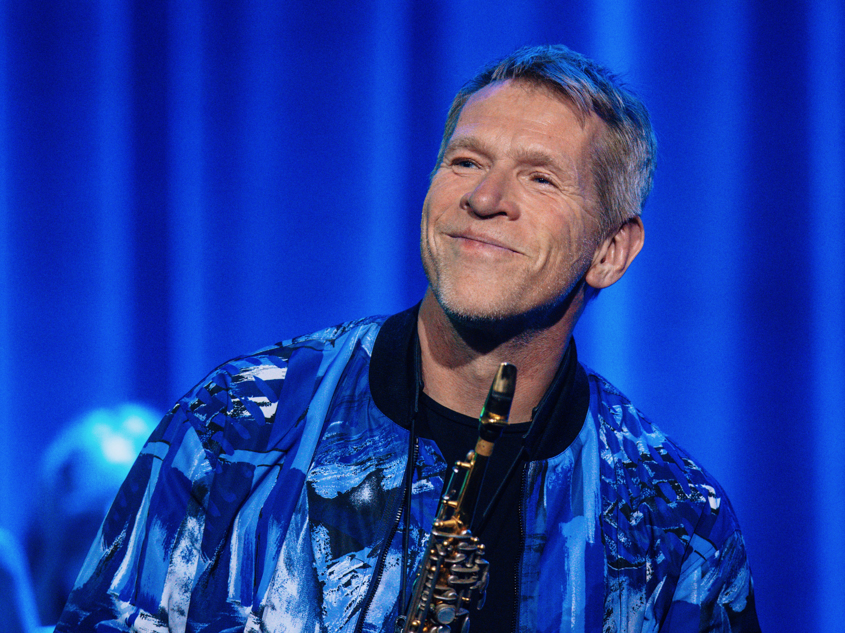 Anders Paulsson, klädd i blå jacka, på scen med sopran saxofon i hand.