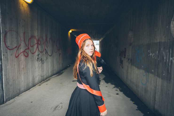 Halvkroppsbild på Kajsa stående inne i en gångtunnel iförd samiska kläder.
