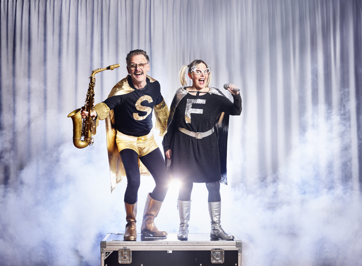 Musikhjältarna står med saxofon och mikrofon i rök och motljus.  